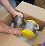 hands putting a aircraft part inside a carton shipping box